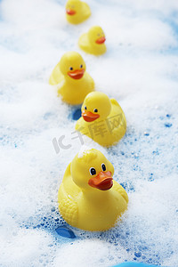 泡泡摄影照片_泡泡浴中的一排橡胶鸭高视图特写