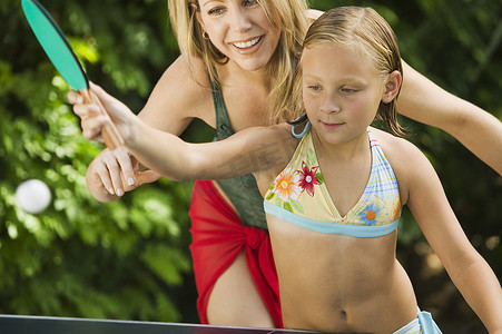 小女孩和她快乐的妈妈在户外打乒乓球