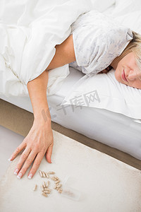 女人睡在床上，前景是药丸