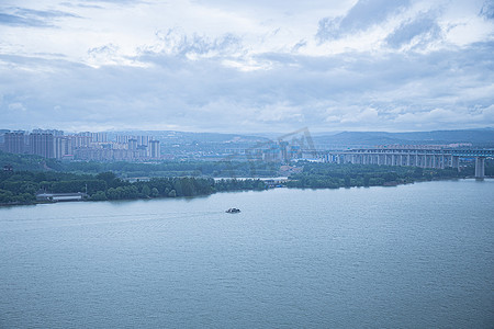 阴天雨天摄影照片_在雨天眺望行驶在河中的船只风景摄影图