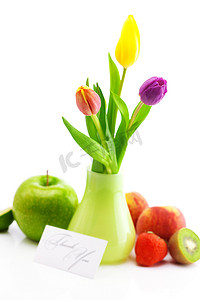 花瓶中的彩色郁金香、水果和一张卡片，感谢伊索拉