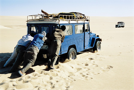 车在沙漠摄影照片_男子在沙漠中推着吉普车