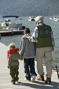 尺寸对比摄影照片_祖父和孙子在码头散步的后视图