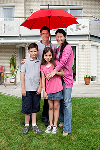 幸福的家庭在他们家外的一把伞下