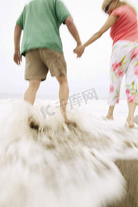 情侣牵手在海浪中漫步