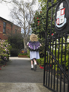 一个小女孩跑出校门的全长后视图像