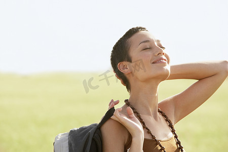 放松的女性徒步者在田野里闭着眼睛晒太阳