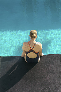 坐在泳池边缘的年轻女游泳运动员的高视角