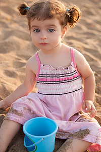 人像摄影照片_蓝眼睛黑发幼儿女孩在沙滩玩耍