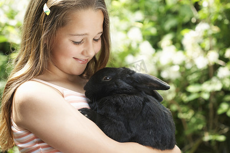 快乐的小女孩在后院抱着兔子