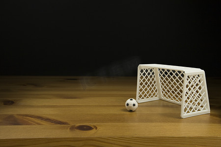 深色木桌面摄影照片_关闭在一张木桌上的桌面足球和球门柱，