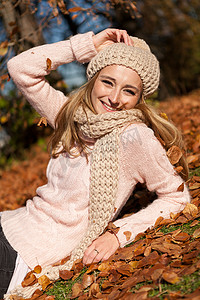 秋天带着帽子和围巾在户外微笑的年轻女人