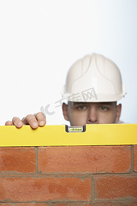 建筑工人使用水平仪检查白色背景下的砖墙