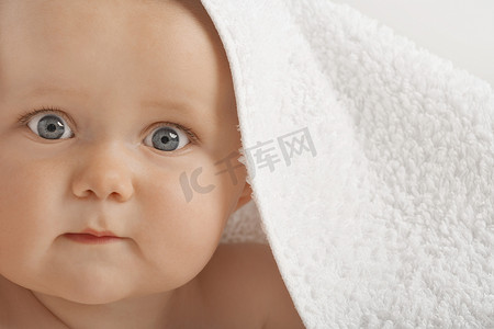 毛巾下蓝眼睛可爱婴儿的特写肖像