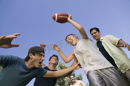 男孩 (13-15) 和一群年轻人低角度踢足球。