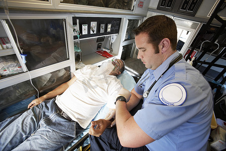 车辆爱心摄影照片_男性 EMT 专业人士在救护车内为一名男子脉搏
