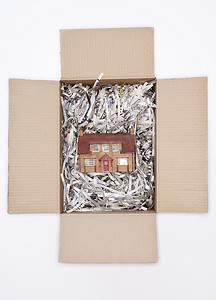 坤3d模型摄影照片_纸板箱中的模型房子，白色背景上有碎纸