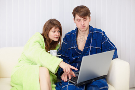配偶们穿着晨衣坐在沙发上，带着笔记本电脑