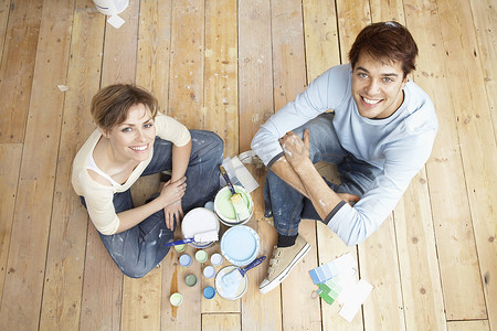 家装三折页摄影照片_坐在木地板上的幸福夫妇的高角度肖像与绘画工具