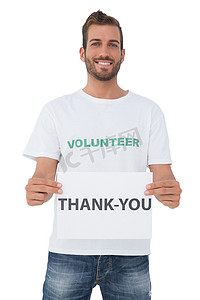 拿着‘谢谢’纸的微笑的年轻男性志愿者