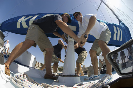 帆船比赛摄影照片_船员在游艇上操作起锚机的低视角