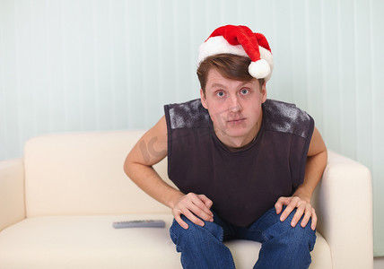 圣诞帽的人坐在沙发上看电视