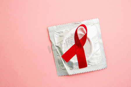 慈善底框摄影照片_包装避孕套上的红色意识丝带