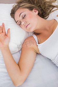 睡觉在白色卧室里的平安的妇女