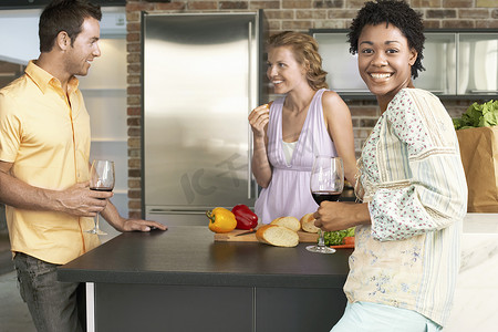 快乐的年轻非洲裔美国女性与朋友在厨房柜台的画像