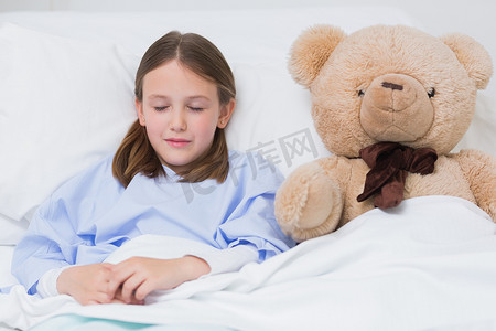 黑孩子摄影照片_孩子躺在床上和泰迪熊一起睡觉