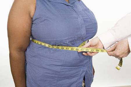 肥胖女性摄影照片_白色背景下测量肥胖女性腹部的手的中段