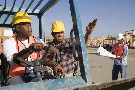 与同事一起驾驶推土机的男子在施工现场指着方向