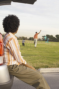 一位非洲裔美国妇女看着公园里玩风筝的男人和孩子