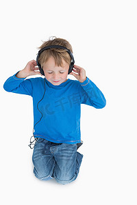 小男孩通过耳机听音乐