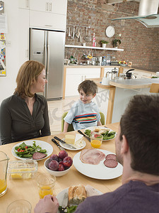 快乐的父母和儿子在厨房的餐桌上吃饭