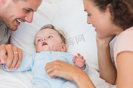 红色烫金首页摄影照片_父母看着躺在床上的男婴