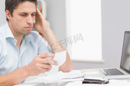 坐着的会计摄影照片_忧心忡忡的男人在家里用笔记本电脑在线支付账单