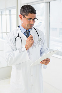 健康报告摄影照片_男性医生在医院阅读报告