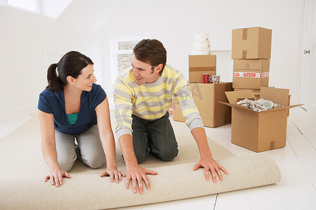 幸福的年轻夫妇在新家铺地毯