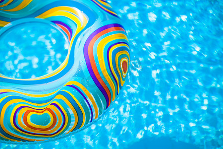 漂浮在蓝色游泳池的可膨胀的五颜六色的橡胶圈