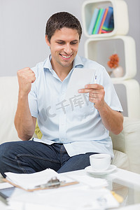坐着的会计摄影照片_微笑的男人在家付账