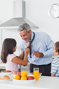 女儿在厨房里和儿子一起修理父亲的领带