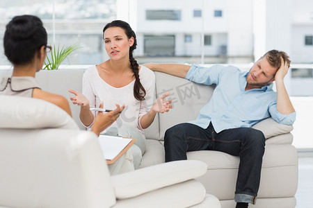 愤怒的夫妇坐在沙发上与治疗师交谈