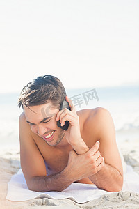 微笑的帅哥在沙滩上打电话