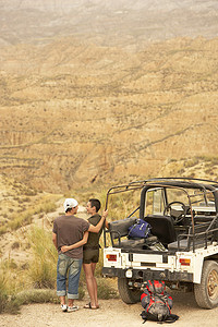 站在四驱车旁的悬崖上看沙漠的恩爱夫妻背影