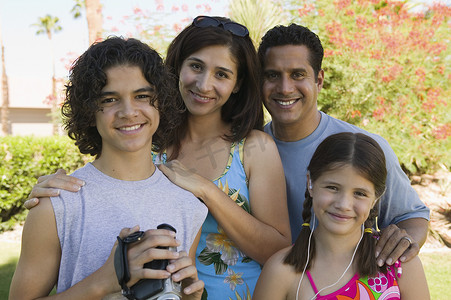 男孩（13-15 岁）拿着摄像机站在户外，妹妹（7-9 岁）和父母的肖像。