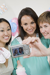 快乐的孕妇和朋友在婴儿送礼会上通过相机自拍