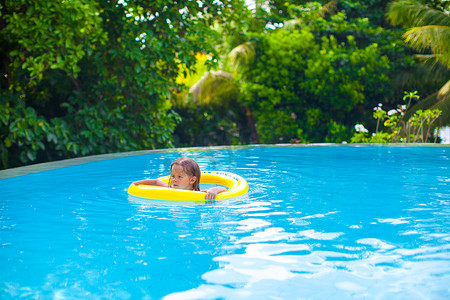小女孩在游泳池的橡胶圈里游泳