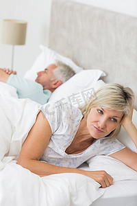 紧张的女人躺在床上的男人旁边