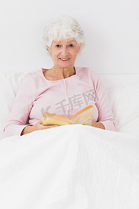 微笑的女人在床上看书